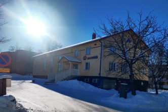 Kuvassa keltainen nuorisoseurantalo aurinkoisessa, talvisessa maisemassa.